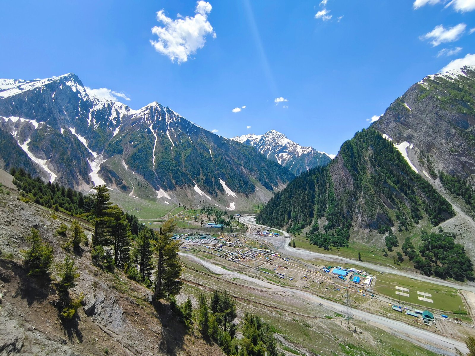 a scenic view of a mountain range with a camp site in the foreground